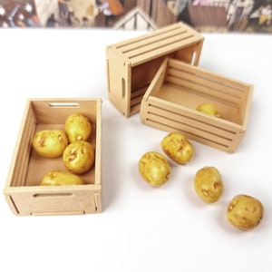 May include: A set of six yellow potatoes in a wooden crate. The crate is made of light brown wood and has a handle on the side. The potatoes are arranged in a single layer in the crate.