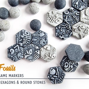 Peut inclure: Marqueurs de jeu avec des motifs de fossiles. L'image montre des tuiles hexagonales grises et des pierres rondes avec des empreintes de fossiles. Le texte sur l'image indique "Fossiles, Marqueurs de jeu, Hexagones et Pierres rondes."