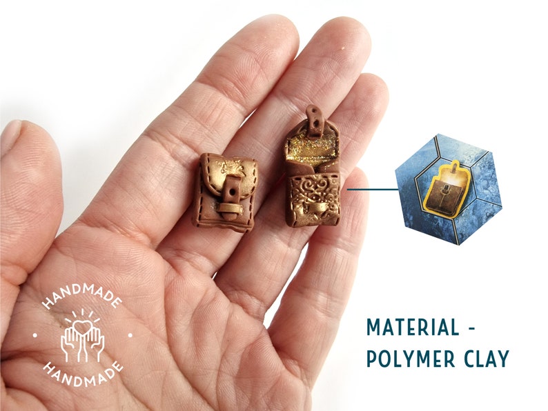 Op de afbeelding: Twee miniatuur bruine leren tassen met gouden accenten en gespen. De tassen zijn gemaakt van polymer clay en worden in een hand getoond. De afbeelding bevat ook een close-up van een van de tassen in een zeshoekig frame.