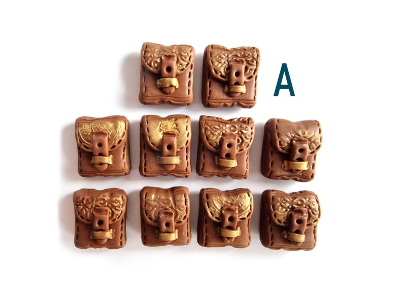 Op de afbeelding: Negen bruine en gouden miniatuur tassen met gespen en stiksels. De tassen zijn in een piramidevorm gerangschikt. De letter "A" is zichtbaar in de rechterbovenhoek van de afbeelding.