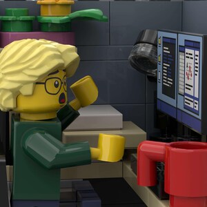Puede incluir: Una figura de Lego con pelo rubio y gafas, sosteniendo dos tazas amarillas, parece sorprendida mientras mira una pantalla de ordenador. Una taza roja est&aacute; sobre un escritorio. La escena est&aacute; ambientada en un entorno de oficina Lego.
