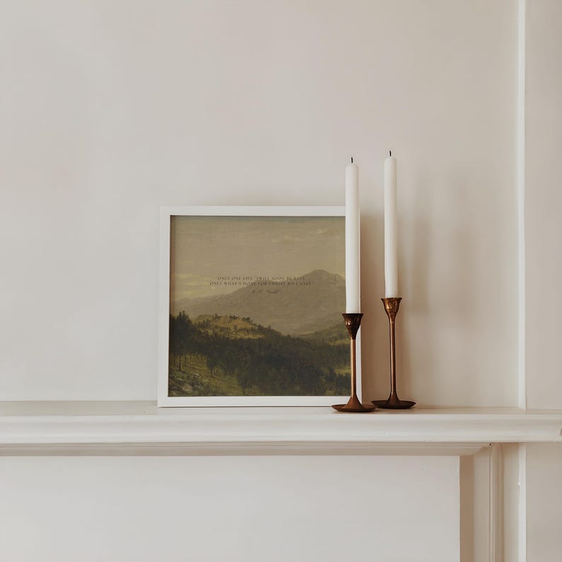 May include: A white framed print of a landscape painting with a quote in the center. The quote reads "Open your eyes and still you won't believe, only what a wilderness surrounds us all." - W.B. Yeats. Two white candles are on a gold candlestick holder on a white mantel.
