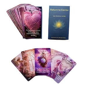 May include: A deck of oracle cards with a purple and pink color scheme. The cards feature images of a heart, a clock, and other mystical symbols. The text on the cards includes phrases like "Return to Center" and "Ruptura de Corazon."