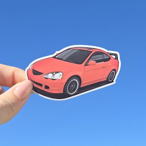 May include: A sticker of a coral-colored sports car with black rims and a black spoiler. The car has a black roof and is set against a bright blue background. The sticker is held by a hand.