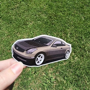 Puede incluir: Una pegatina de un coche coupé marrón con capó negro y ventanas tintadas negras. El coche tiene una llanta blanca en la rueda delantera del lado del conductor.