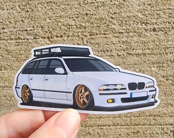 May include: A white car with a black roof rack. The car has gold wheels and a license plate.