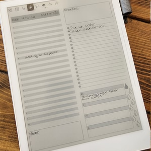 Può includere: Un e-reader grigio e bianco con un calendario, una lista di cose da fare e una sezione di note. La data è 4/1/22. La lista di cose da fare include "Pick up order" e "Make appointment". La sezione di note include "Scrambled eggs, fresh fruit, coffee".
