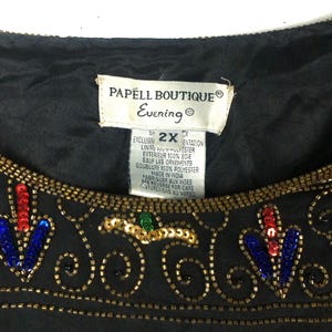 Pu&ograve; includere: Top da sera nero con paillettes, ricamo dorato e un'etichetta bianca che recita "PAPELL BOUTIQUE&reg; Evening S2XX EXCLUSIVELY MENTATION LINING 100% POLYESTER EXTERIEUR 100% SOIE SAUF LES ORNEMENTS DOUBLURE 100% POLYESTER MADE IN INDIA FABRIQUER AUX INDES SEE REVERSE FOR CARE INSTRUCTIONS AU VERSO"