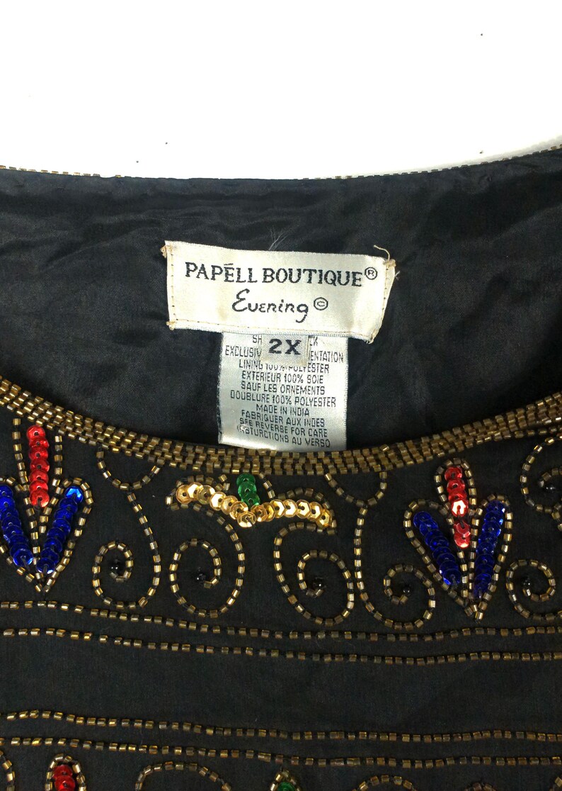 Pu&ograve; includere: Top da sera nero con paillettes, ricamo dorato e un'etichetta bianca che recita "PAPELL BOUTIQUE&reg; Evening S2XX EXCLUSIVELY MENTATION LINING 100% POLYESTER EXTERIEUR 100% SOIE SAUF LES ORNEMENTS DOUBLURE 100% POLYESTER MADE IN INDIA FABRIQUER AUX INDES SEE REVERSE FOR CARE INSTRUCTIONS AU VERSO"