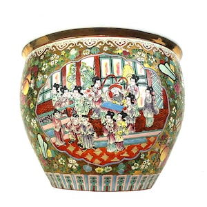 May include: A large, round ceramic planter with a detailed, colorful Asian-inspired design. The planter features a gold rim and a painted scene of figures in traditional clothing. The background is a mix of green, pink, and gold floral patterns.