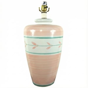 May include: A ceramic table lamp with a pink and white painted design. The lamp features a light pink base with horizontal brushstrokes. A white band with teal stripes and pink leaf accents encircles the lamp. The lamp has a brass-colored socket.