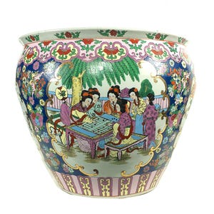 May include: A large ceramic fishbowl planter featuring a colorful hand-painted scene of figures playing a board game under a willow tree. The exterior is decorated with intricate floral patterns, gold accents, and a blue background border.