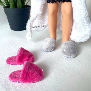 Op de afbeelding: Twee paar fluffy pantoffels. Een paar is grijs en het andere paar is roze. De pantoffels liggen op een wit oppervlak.