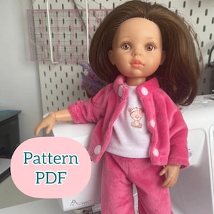 May include: A pink and white doll outfit with a white shirt featuring a cartoon bear design. The outfit includes a pink jacket and matching pants. The text "Pattern PDF" is visible in the image.