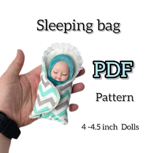 May include: PDF pattern for a sleeping bag for 4-4.5 inch dolls. The sleeping bag is gray and teal with a chevron pattern and white lace trim.