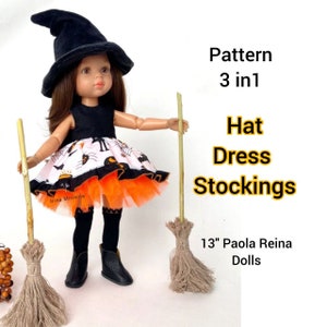 Puede incluir: Una muñeca Paola Reina de 33 cm vestida con un disfraz de Halloween negro y naranja. La muñeca lleva un sombrero de bruja negro, un vestido negro y blanco con tul naranja, medias negras y botas negras. La muñeca sostiene dos escobas.