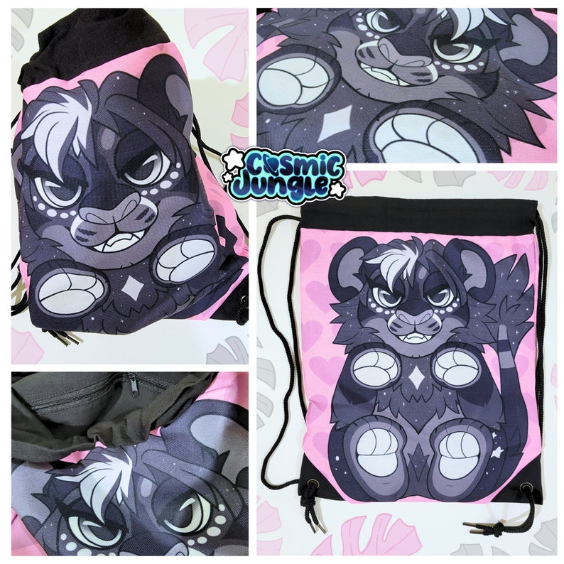 May include: A pink drawstring bag with a black furry creature with white markings on a pink background. The creature has a black nose and white eyes. The bag has a black drawstring and black handles. The text "Cosmic Jungle" is printed on the bag.