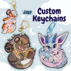 Può includere: Tre portachiavi personalizzati con disegni di animali dei cartoni animati. I portachiavi sono realizzati in acrilico trasparente e presentano una tigre rosa, un leone marrone e una creatura pelosa blu e rosa. I portachiavi sono attaccati ad anelli metallici dorati e argentati.