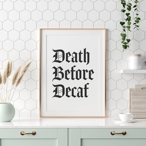 Könnte beinhalten: Ein gerahmter Druck mit dem Text "Death Before Decaf" in einer schwarzen gotischen Schrift auf weißem Hintergrund.