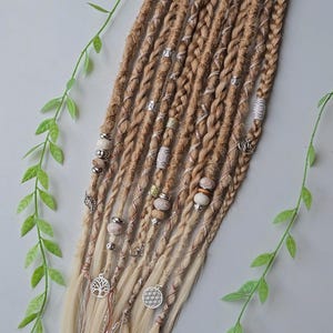May include: A set of blonde synthetic dreadlocks with brown and white beads, silver charms, and a tree of life charm.