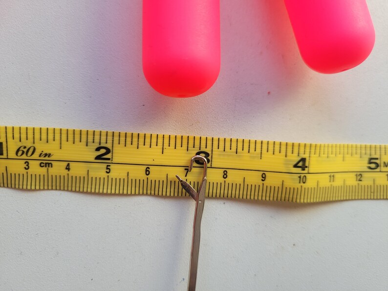 Peut inclure: Un gros plan d'un m&egrave;tre ruban jaune avec des marques noires, indiquant les pouces et les centim&egrave;tres. Le ruban mesure un crochet en argent, qui mesure environ 17,8 cm de long.