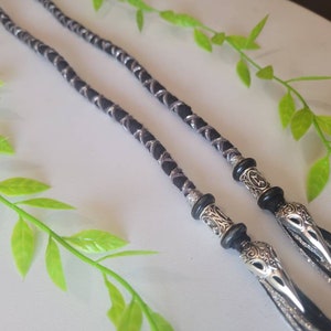 May include: Two black and silver braided cords with silver bird head charms at the ends. The cords are braided with a silver thread.