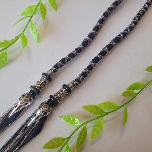 May include: Two black and silver braided cords with silver and black bird head charms at the ends.