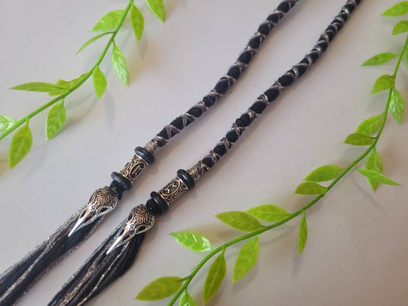 May include: Two black and silver braided cords with silver and black bird head charms at the ends.