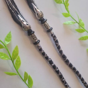 May include: Two black and silver braided cords with decorative silver bird head beads at the ends.