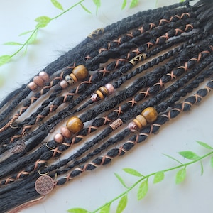 Peut inclure: Dreadlocks synthétiques noirs avec des perles et des breloques brunes et dorées. Les dreadlocks sont attachées ensemble avec une ficelle brune.