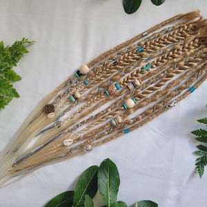 May include: A set of blonde synthetic dreadlocks with blue and white accents and various beads. The dreadlocks are braided and have a natural, bohemian style.