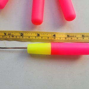 Peut inclure: Un crochet en plastique rose et jaune avec un crochet en m&eacute;tal. Le crochet mesure 12,7 cm de long et est mesur&eacute; &agrave; l'aide d'un m&egrave;tre ruban jaune.
