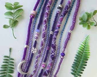 Hårlinda, dreadlocks och flätor. 50-65 cm lager på lager. Dreadlocks i lila toner. Blandade kristaller. Hippie, boho, festivalfrisyr.
