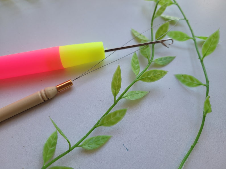 Peut inclure: Gros plan sur deux aiguilles &agrave; tricoter. L'une est une aiguille en plastique rose et jaune avec un crochet en m&eacute;tal. L'autre est une aiguille en bois avec une pointe en m&eacute;tal dor&eacute;.