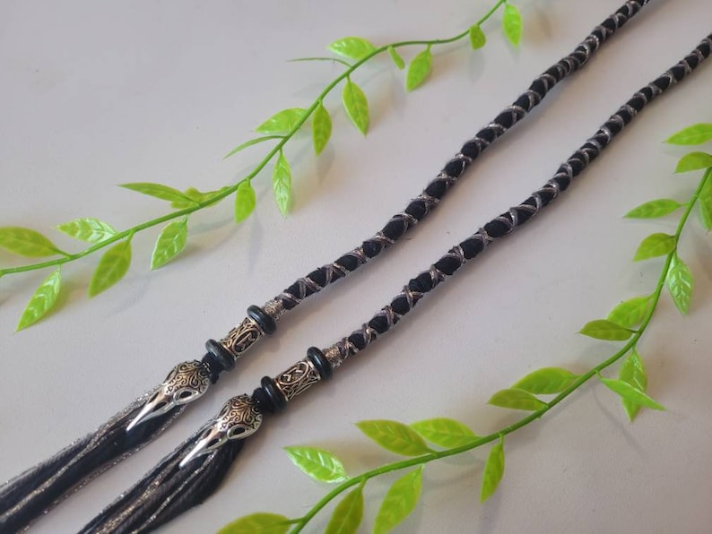 May include: Two black and silver braided cords with silver bird head charms at the ends.
