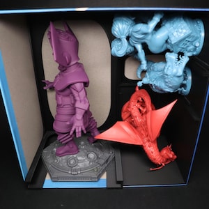 Puede incluir: Una figura en miniatura de Galactus púrpura se encuentra sobre una base gris con una figura en miniatura de dragón rojo volando detrás de ella. Una figura en miniatura femenina azul se encuentra en el lado derecho de la imagen.
