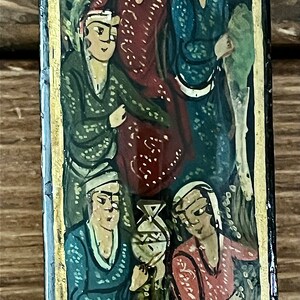 May include: A vintage painting depicting four figures in a forest setting. The figures are dressed in colorful, patterned clothing. The painting is framed in a black and gold frame.