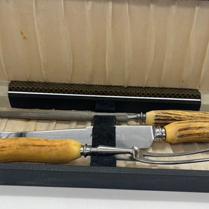 May include: A set of three silver-plated knives with stag horn handles in a black velvet-lined box.