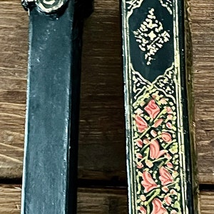 May include: Two black wooden boxes with intricate gold and red floral designs. The boxes are decorated with gold leaf and have a traditional, ornate style.