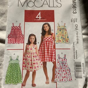 May include: A sewing pattern for four different styles of girls' dresses. The pattern is for sizes 7-8, 10-12, and 14. The pattern is called McCall's M5613 CHJ.