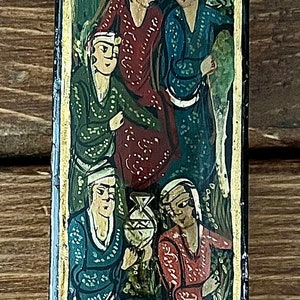 May include: A black rectangular box with a gold trim and intricate floral designs painted in red, green, and gold. The box features a scene of five people in colorful clothing, painted in a traditional style.