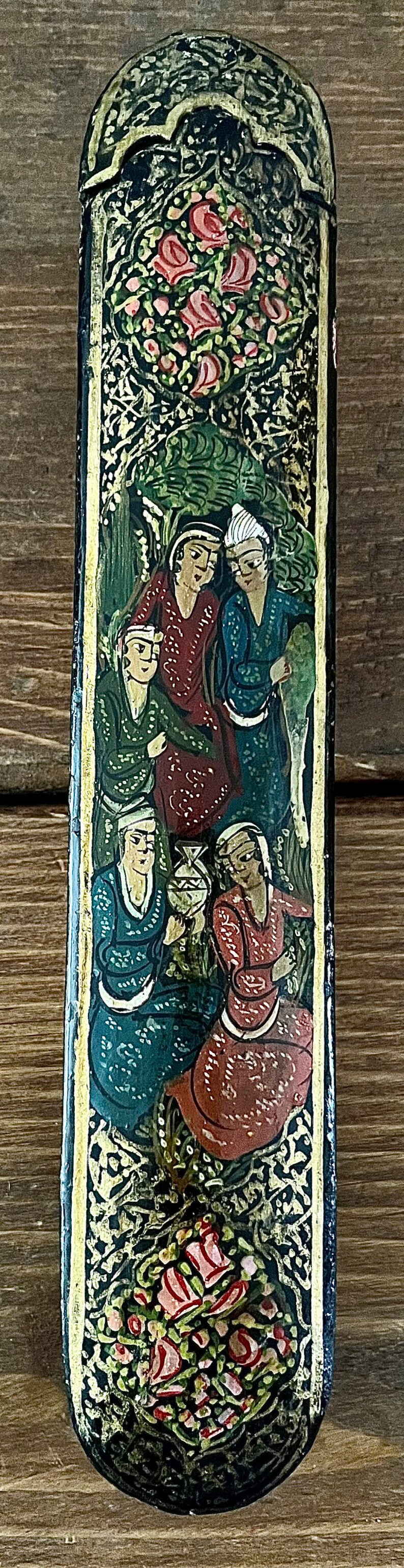 May include: A black rectangular box with a gold trim and intricate floral designs painted in red, green, and gold. The box features a scene of five people in colorful clothing, painted in a traditional style.