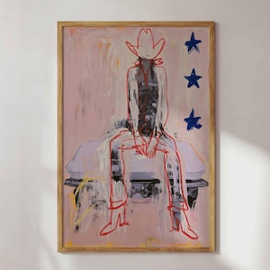 May include: A framed wall art print featuring a stylized illustration of a figure wearing a cowboy hat and boots, rendered in bold red outlines against a pale pink background. Three dark blue stars are positioned vertically on the right side.
