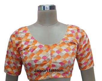 May include: A pink, orange and white embroidered blouse with a scalloped pattern. The blouse has a scoop neckline and short sleeves. The text "Jaipuri fashion" is printed on the front of the blouse.
