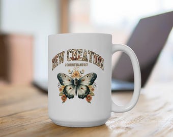 May include: White ceramic mug featuring a butterfly design with the text "NEW CREATION 2 Corinthians 5:17". The butterfly has gray and cream-colored wings, surrounded by orange and yellow flowers. The mug has a large handle.
