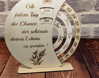 Könnte beinhalten: Holzkalender für den Schreibtisch mit dem Zitat: "Gib jedem Tag die Chance, der schönste Tag deines Lebens zu werden!" Der Kalender hat ein kreisförmiges Design mit drehbaren Ringen für jeden Monat des Jahres. Das aktuelle Datum ist auf den 20. Januar eingestellt.