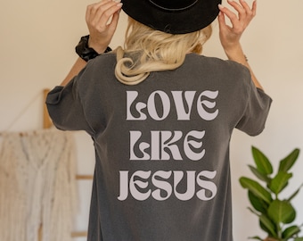 May include: A dark gray t-shirt with the text "LOVE LIKE JESUS" printed in a light gray color on the back.