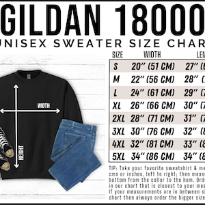 Op de afbeelding: Zwart Gildan 18000 unisex sweatshirt met een maattabel. De tabel geeft de maten S tot en met 5XL weer, met breedte- en lengtematen in inches en centimeters. De afbeelding bevat ook sneakers en een blauwe jeans.