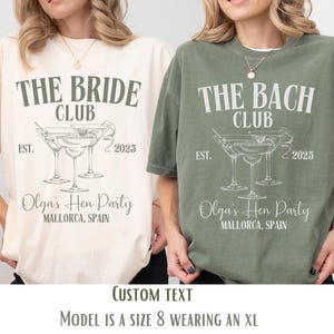May include: Two white t-shirts with a grey graphic design. The text on the shirts reads "The Bride Club" and "The Bach Club". Both shirts feature a drawing of three martini glasses with olives. The text "Est. 2025" and "Olga's Hen Party Mallorca, Spain" is also included on the shirts.