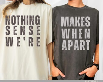 Puede incluir: Dos camisetas, una crema y otra carbón, cada una con un diseño de texto audaz y desgastado. La camiseta crema dice "NOTHING SENSE WE'RE" y la camiseta carbón dice "MAKES WHEN APART". La parte inferior de la imagen dice "AVAILABLE IN SWEATSHIRT AND HOODIE".